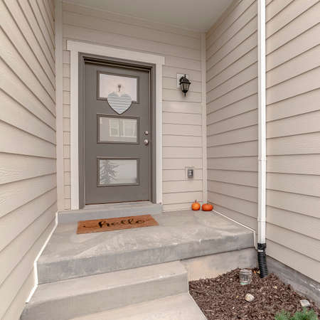 Square Small white entrance walkway and front door to a wooden clad house in a receding viewの写真素材