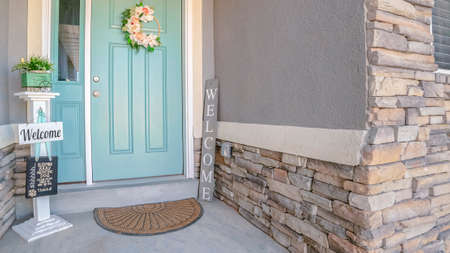Panorama frame Green painted front door to a suburban house with floral wreath and Welcome sign...