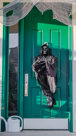 Vertical frame A grim reaper decoration on a green front doorの写真素材