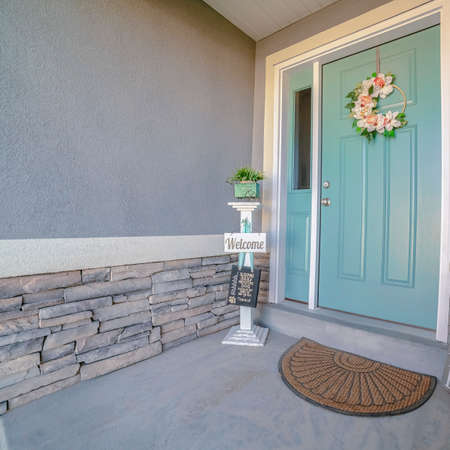 Square frame Welcome signs alongside a green front door to a house decorated with a floral wreath under a small porchの写真素材