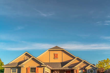 House exterior with view of the gable roof with gable windows against blue sky. Architectural roof...