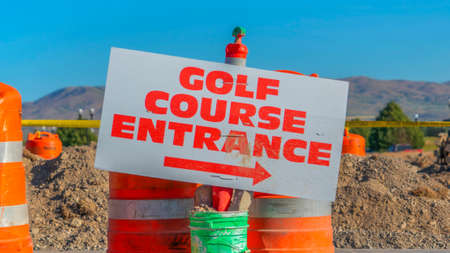 Panorama frame Road under construction with golf course entrance sign and traffic barrels