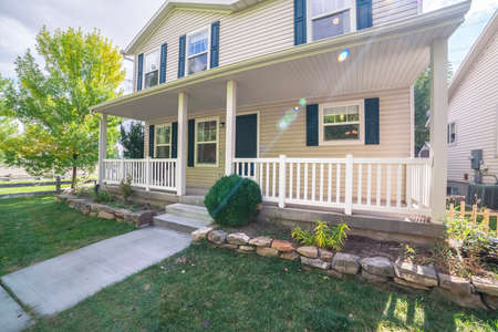 White timber house with shutters and front veranda with wooden banister in neat green lawnsの写真素材