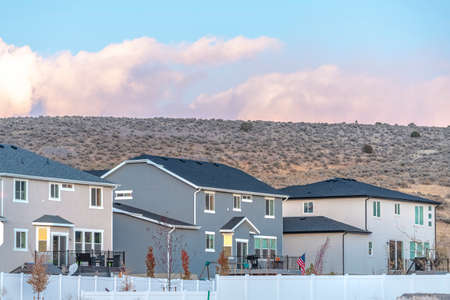Row of modern urban homes in a housing complex with white cloud formations over a mountain behind