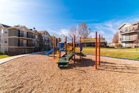Small kids playground in an urban park overlooked by flats and apartment blocks in landscaped...