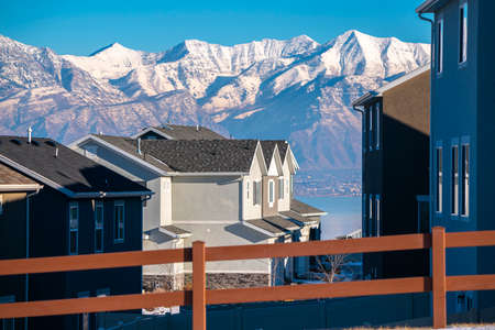 Majestic snow capped mountains above Utah Valley in winter viewed past houses in an estate on the shore of the Lakeの写真素材