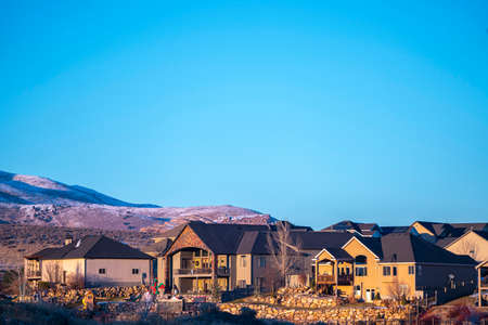 Distant view of cozy American houses against snow covered hills in Utah valley and clear blue sky on sunny dayの写真素材