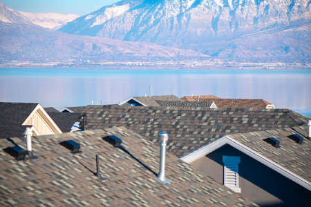 Roofs of various residential houses against Utah Lake and mountains in a sunny day in United States
