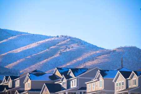 Low angle of the street with traditional American single family houses against the hills covered with snow in winter seasonの写真素材