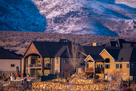 Zoomed photo of a beautiful brown American houses with stone front yard decoration and bare trees,...