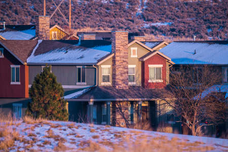 Houses in a winter landscape at sunset with light snow on the ground and rooftops in close upの写真素材