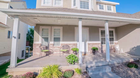 Panorama Modern urban house with covered front veranda and small neat front garden with flowerbed and plantsの写真素材