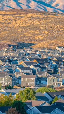 Vertical Houses and green trees in a town in Utah valley with arid landscape of mountainous terrain in backgroundの写真素材