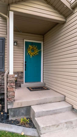 Vertical frame Concrete steps leading to a front door of a wooden house with small covered entry porch and stone feature wallの写真素材