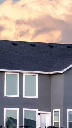 Vertical frame Grey double storey house against stormy white clouds at sunset in a close up cropped viewの写真素材