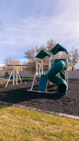 Vertical Kids playground in a walled park or estate with slides and climbing frames in evening light