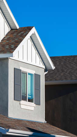 Vertical frame Low angle close-up on traditional American houses with brown roof against clear blue...