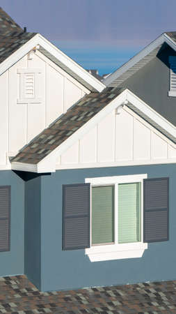 Vertical Grey and white house facade with shutters in close up in warm light
