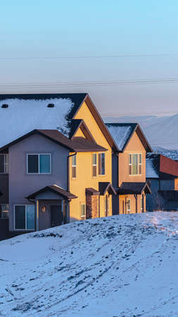 Vertical American houses on small town street in winter with snow on the ground and mountains of Utah visible in backgroundの写真素材