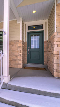 Vertical frame Snow covered front steps and porch with white railings at the entrance to a house...