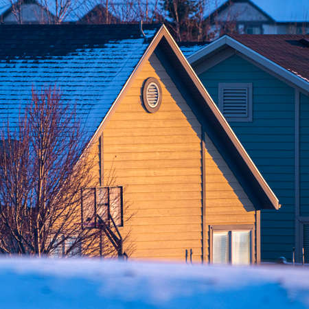Square House roof covered in snow in golden evening lightの写真素材
