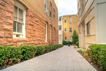 Pathway amid residential buildings leading to a fire pit in the distance. The walkway if lined with...