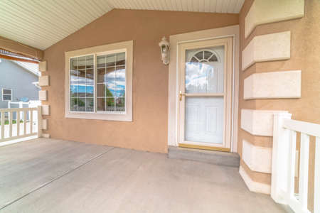 Front porch white front door with glass panes and windows at the home entrance. EXterior of a house...
