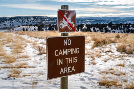 Warning signs with snow covered hill and cloudy sky in the scenic background. Camping is prohibited in the vast area blanketed with snow during winter season.の写真素材