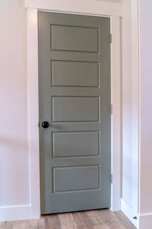 Gray door with matte black door knob and white door frame against wall. Architectural details inside...