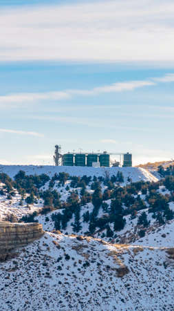 Vertical frame Industrial building on top of a rugged snowy mountain against cloudy sky. A stunning...