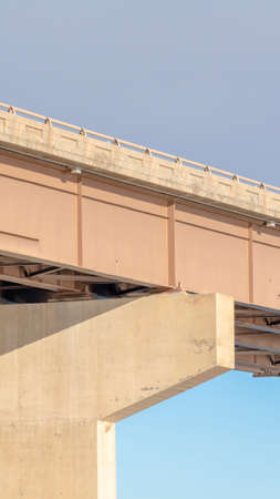 Vertical frame View beneath a stringer bridge with massive abutment that supports the deck. Cloudy...