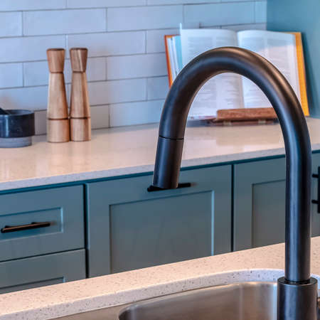 Square Double bowl sink and black faucet on kitchen island against cooktop and counter. Cooking...