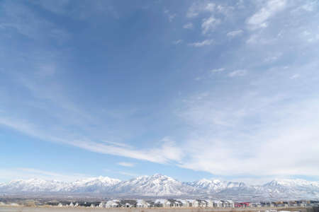 Panoramic view of South Jordan City neighborhood and Wasatch Mountains in winter. Vast blue sky with clouds is over the picturesque landscape.の写真素材
