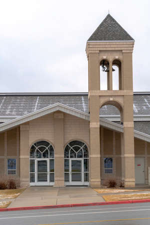 Church facade with glass front doors and modern belfry tower against cloudy skyの写真素材