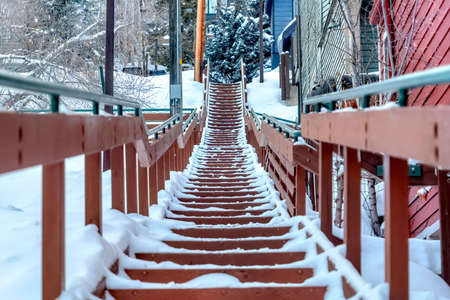 Stairway along colorful neighborhood homes on scenic snow covered hill in winterの写真素材