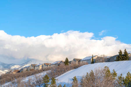 Row of homes on pristine snowy slope with unobstructed view of Wasatch Mountains. The scenic neighborhood is surrounded by frosted nature views in winter.の写真素材