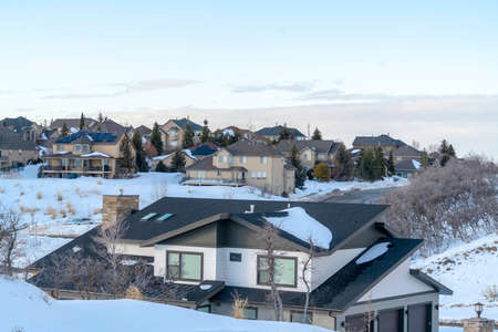 Homes of snowed in town situated amid scenic terrain of Wasatch Mountains. The neighborhood has a fantastic view of frosted nature and cloudy sky in winter.の写真素材