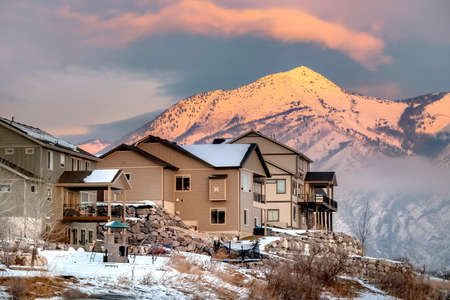 Houses on hill with scenic view of Wasatch Mountains and cloudy sky at sunset. Picturesque residential and nature scenery in Utah Valley in winter.の写真素材