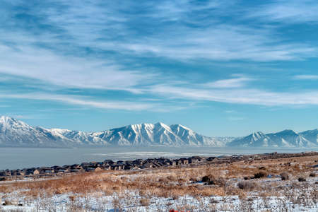 Rugged Wasatch Mountains and icy Utah Lake with snowy terrain in the foreground. Lakefront...