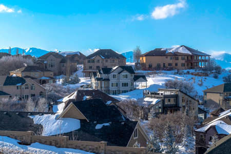 Pristine Wasatch Mountain landscape with houses on sweeping snowy terrain. Towering peaks and blue...