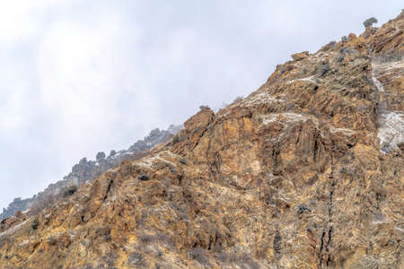 Snow dusted terrain of the rocky Prvo Canyon in Utah with cloudy sky background. Some snow can be...
