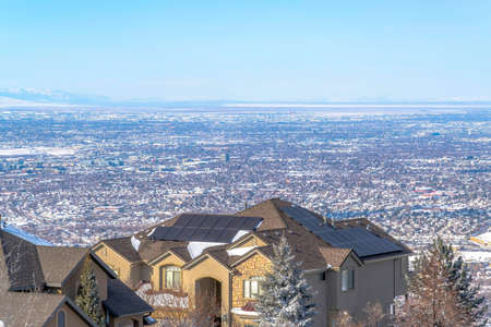 Luxury homes with view of the vast residential valley and Wasatch Mountains. A picturesque winter scenery and blurry blue sky over the horizon.の写真素材
