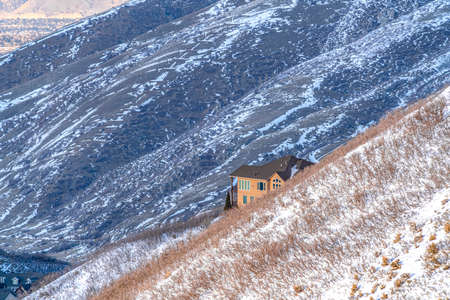 Home amidst sweeping terrain of Wasatch Mountains blanketed with snow in winter. Scenic frosted nature views surround the house and provides a fantastic background.の写真素材