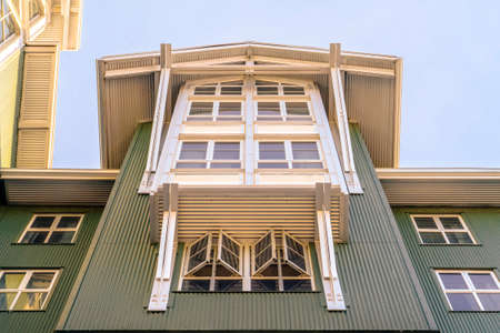 Home with cottage pane windows and gable roof viewed from below against skyの写真素材