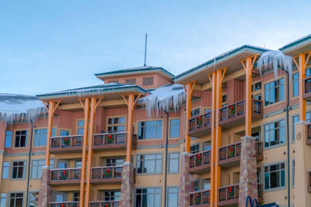 Residential building with fresh snow and sharp icicles on the roof in winterの写真素材