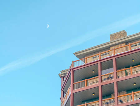 Snow on the roof and balconies of a residential building on a sunny winter day. Stone chimney wall and pale blue sky can also be seen in this landscape.の写真素材