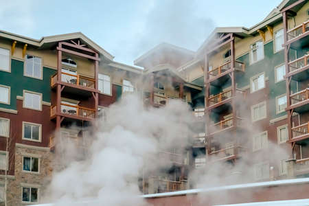 Residential building exterior with steam in the foreground on a cold winter day