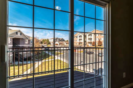 Urban street viewed through a cottage pane window with landscaped lawns and apartment complexes