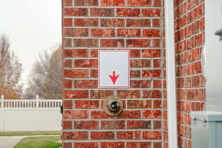 Exterior brick wall with arrow pointing to fire sprinkler on an urban building in close up