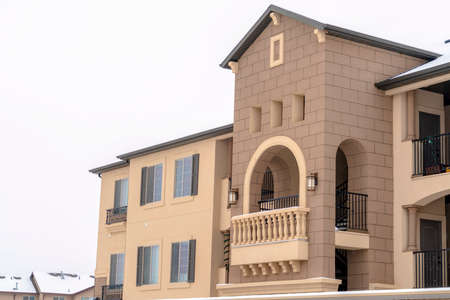 Apartment with snowy front gable roof and balustrade on the arched balcony. Exterior of a...